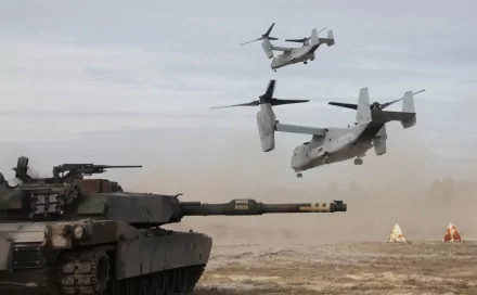 An M1 Abrams tank sits on a dusty terrain while two Ospreys fly overhead, capturing a dynamic military scene in a high-definition wallpaper.