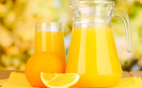 A refreshing display of orange juice in a pitcher and glass, accompanied by an orange and a slice, set against a warm, colorful background. HD PC desktop wallpaper.