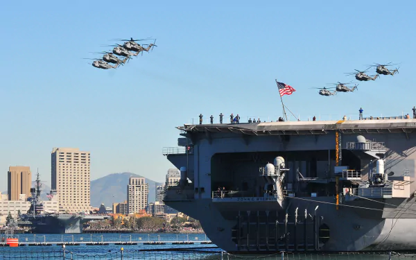 Military Sikorsky CH-53E Super Stallion helicopters fly in formation above a naval ship with an American flag, set against a city skyline in this HD desktop wallpaper.