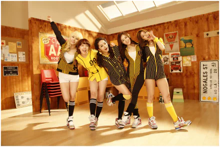 HD PC desktop wallpaper featuring Girl’s Day in coordinated yellow and black outfits, posing cheerfully in a sunlit music-themed room.
