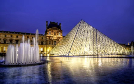 A stunning view of the Louvre Pyramid illuminated at night, with a tranquil fountain in the foreground, showcasing the iconic architecture of Paris in vibrant detail.