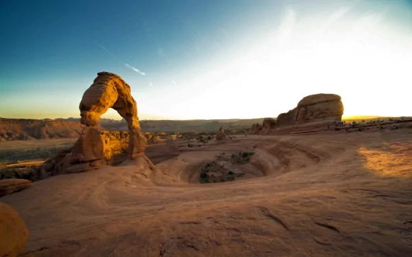 A stunning HD wallpaper showcasing a majestic canyon landscape, featuring a prominent natural arch against a serene sunset sky, capturing the beauty of nature.