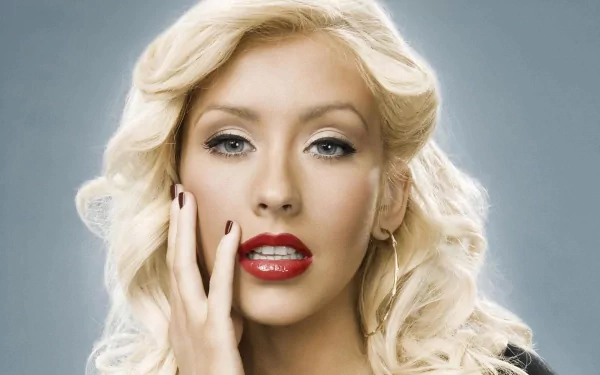 A stunning HD desktop wallpaper featuring Christina Aguilera, showcasing her glam look with blonde curls, red lips, and a striking pose, embodying the essence of music and artistry.