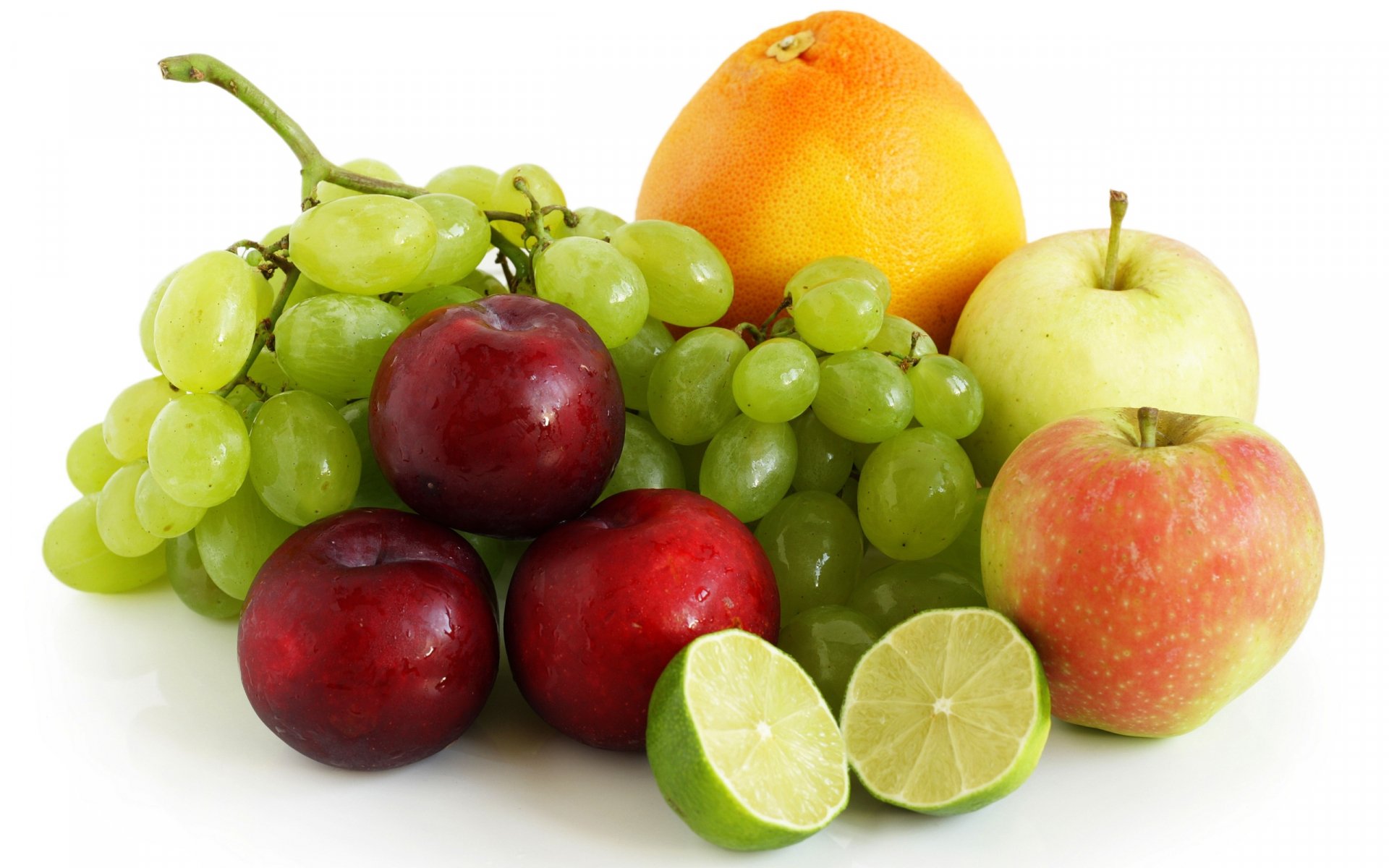 HD PC desktop wallpaper featuring a colorful arrangement of fresh fruit, including green grapes, plums, apples, grapefruit, and a sliced lime on a white background.