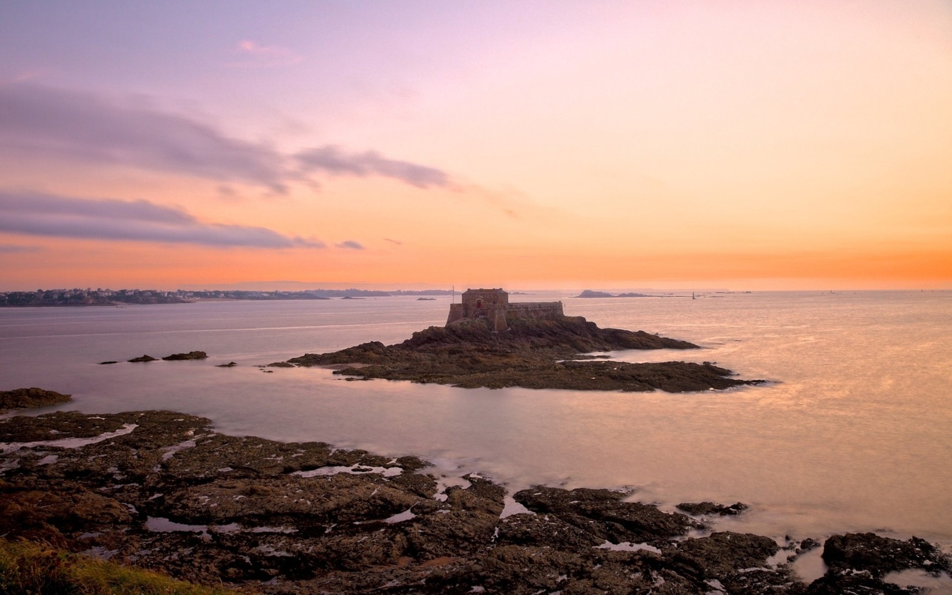 HD PC desktop wallpaper capturing a serene ocean scene at sunset with a small rocky island and soft pastel skies in a natural coastal setting.