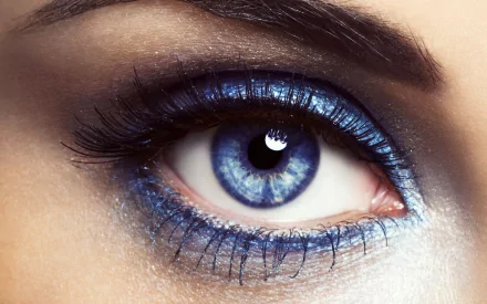 A close-up of a woman's eye featuring striking blue makeup, showcasing detailed lashes and vibrant colors, designed as a high-definition desktop wallpaper and background.
