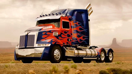 HD desktop wallpaper featuring Optimus Prime from Transformers: Age of Extinction, showcasing him in truck form with vibrant flames and a scenic desert background.