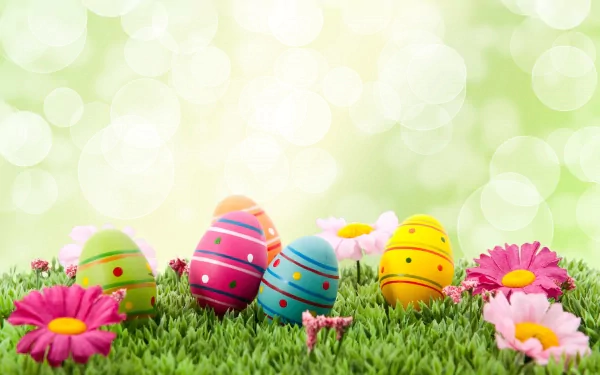 A vibrant Easter-themed desktop wallpaper featuring colorful painted eggs nestled in lush green grass, surrounded by cheerful pink flowers and a soft bokeh background.
