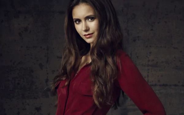 HD desktop wallpaper featuring celebrity Nina Dobrev, showcasing her in a striking pose with a confident expression, dressed in a red top against a textured background.