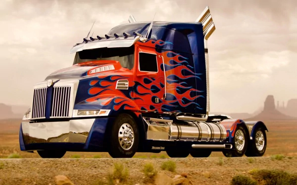 HD desktop wallpaper featuring Optimus Prime from Transformers: Age of Extinction, showcasing him in truck form with vibrant flames and a scenic desert background.
