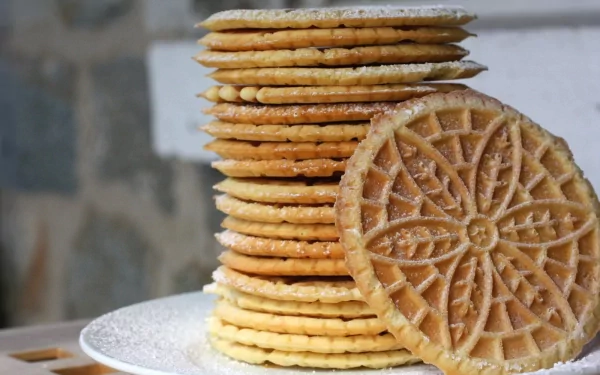 A stack of golden, intricately patterned cookies dusted with powdered sugar, set on a plate with a blurred background, creating a delightful food-themed desktop wallpaper.