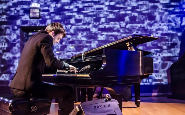 5K Ultra HD PC desktop wallpaper of a pianist performing on a grand piano against a textured blue-lit stage backdrop, a music-themed high-resolution performance scene.