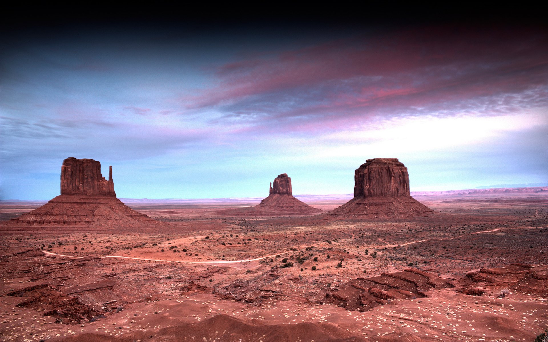 HD PC desktop wallpaper showcasing a vast desert landscape with three prominent rock formations under a dramatic, colorful sky.