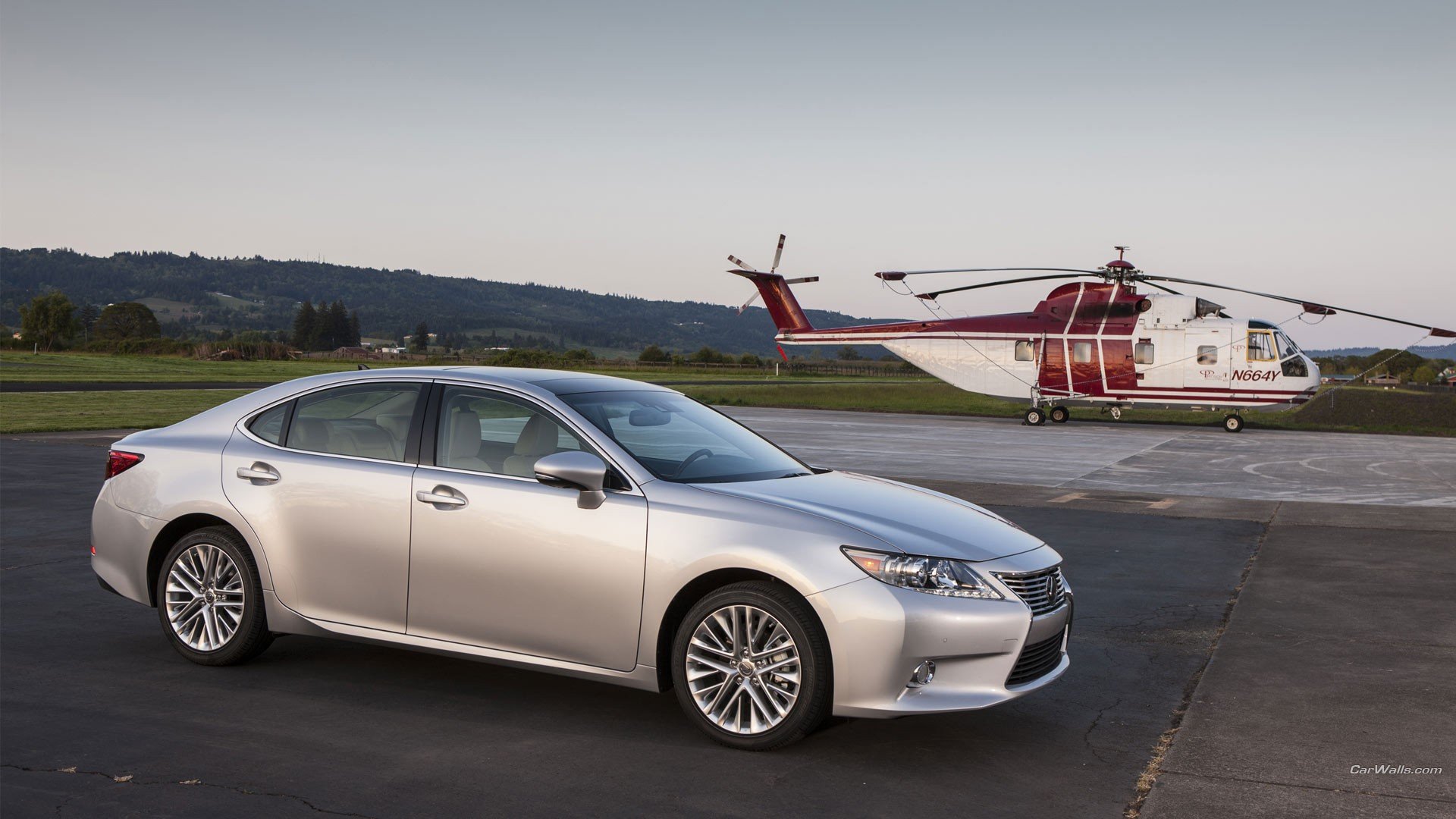 HD desktop wallpaper featuring a silver Lexus ES parked on an airfield with a red and white helicopter in the background.