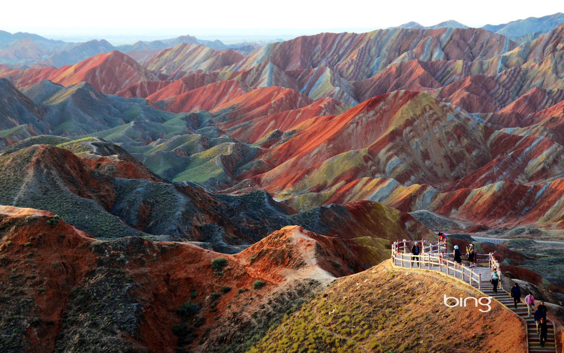 A vibrant landscape of rolling hills in China, showcasing striking orange and red rock formations. This HD image serves as a stunning desktop wallpaper and background.