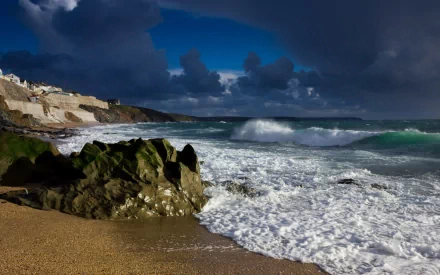 A dramatic coastline scene featuring rocky formations and crashing waves under a moody sky, capturing the raw beauty of nature as an HD desktop wallpaper.