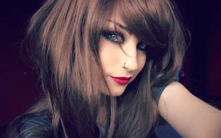 A close-up of an emo woman with striking blue eyes and dark red lips, featuring long brown hair. The image serves as an HD desktop wallpaper and background.
