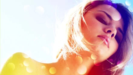 HD desktop wallpaper featuring a model with sunlit hair against a soft pastel background, subtly accented with bokeh light effects.