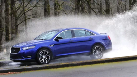Blue Ford Taurus SHO sedan splashing through water on a wet road, HD PC desktop wallpaper and background.