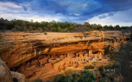 A stunning HD desktop wallpaper of Mesa Verde National Park’s Cliff Palace, showcasing ancient man-made cliff dwellings beneath a dramatic sky.