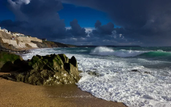 A dramatic coastline scene featuring rocky formations and crashing waves under a moody sky, capturing the raw beauty of nature as an HD desktop wallpaper.
