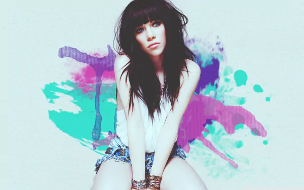 HD PC desktop wallpaper: portrait of a young female pop-singer–styled figure seated against vibrant watercolor paint splashes, music-themed background.