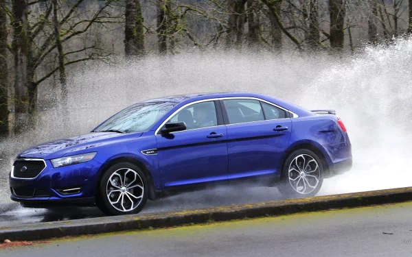 Blue Ford Taurus SHO sedan splashing through water on a wet road, HD PC desktop wallpaper and background.
