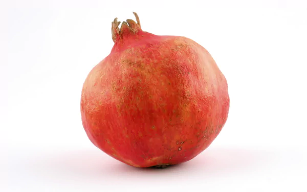 HD desktop wallpaper featuring a vibrant, close-up image of a whole pomegranate against a clean white background.