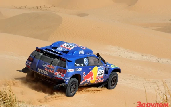 HD PC desktop wallpaper/background: blue Volkswagen Touareg rally vehicle with Red Bull livery kicking up sand as it races across golden desert dunes.