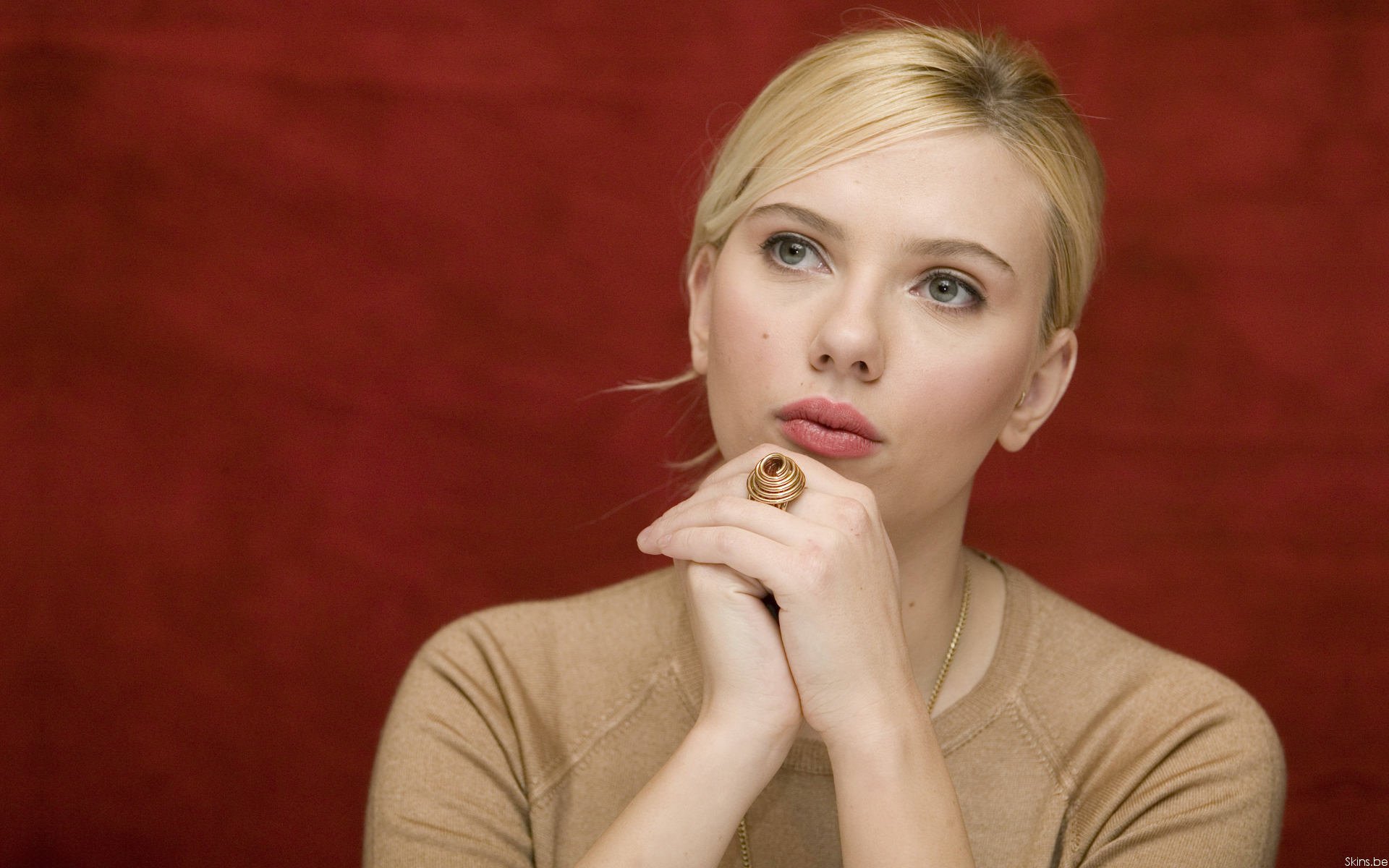Scarlett Johansson, captured in a contemplative pose against a rich red background, featured as a striking HD desktop wallpaper and background.