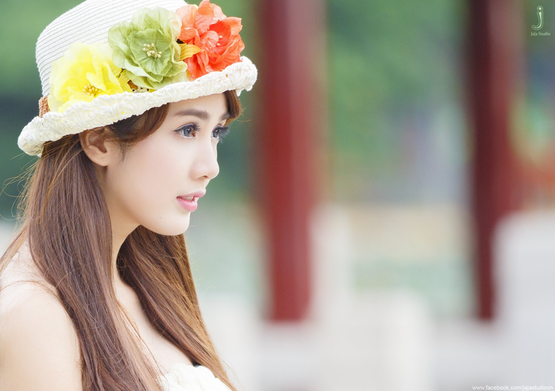 A woman named Linh Napie gazes thoughtfully to the side, wearing a colorful floral hat. The image serves as a vibrant HD PC desktop wallpaper and background.