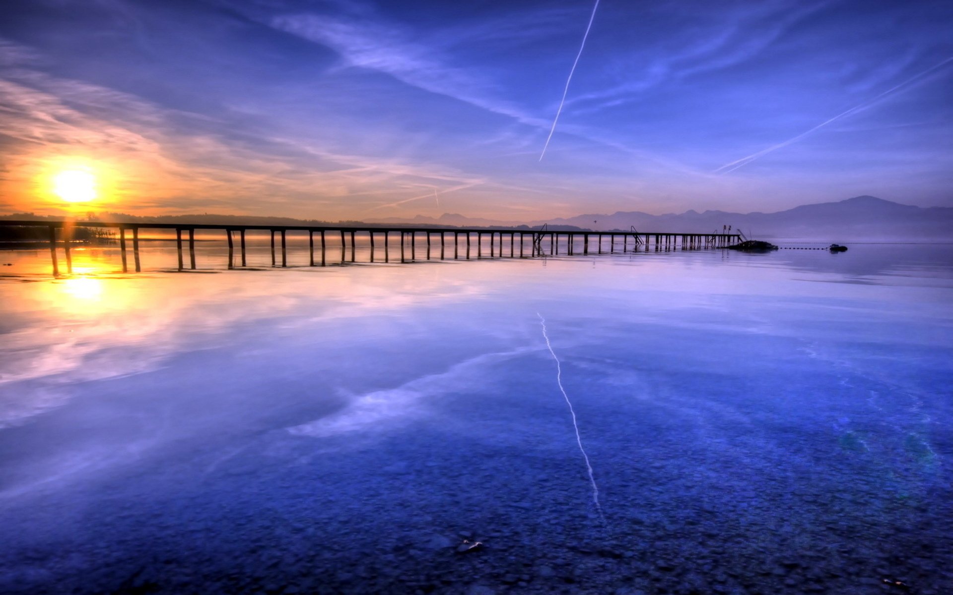 HD desktop wallpaper of a man-made pier extending into calm waters at sunset, with a vibrant sky reflecting on the surface.