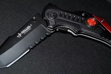 A high-definition desktop wallpaper featuring a sleek Haller one-handed knife, showcasing a black and red design against a dark background.