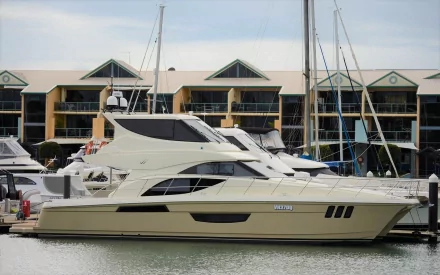 HD PC desktop wallpaper and background of a cream-colored motor yacht (boat/vehicle) moored on calm sea water at a marina with waterfront apartments.