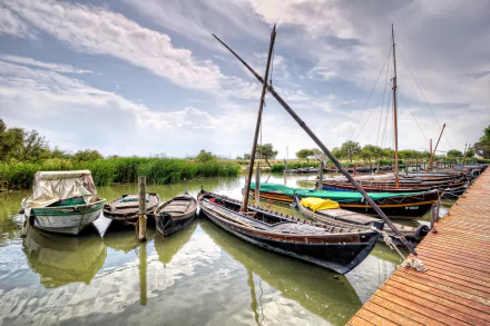 HD desktop wallpaper of various boats docked along a wooden pier on calm water under a partly cloudy sky.