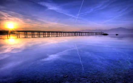 HD desktop wallpaper of a man-made pier extending into calm waters at sunset, with a vibrant sky reflecting on the surface.