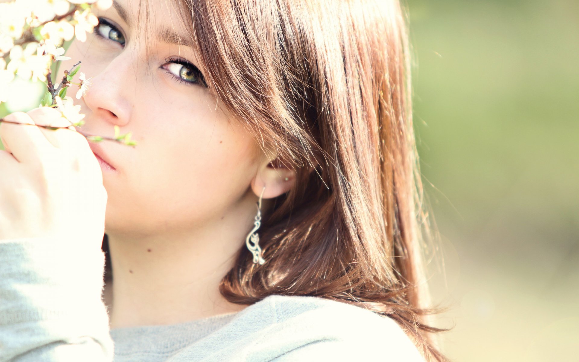 HD PC desktop wallpaper featuring a close-up of a woman’s face with soft natural lighting and a blurred green background.