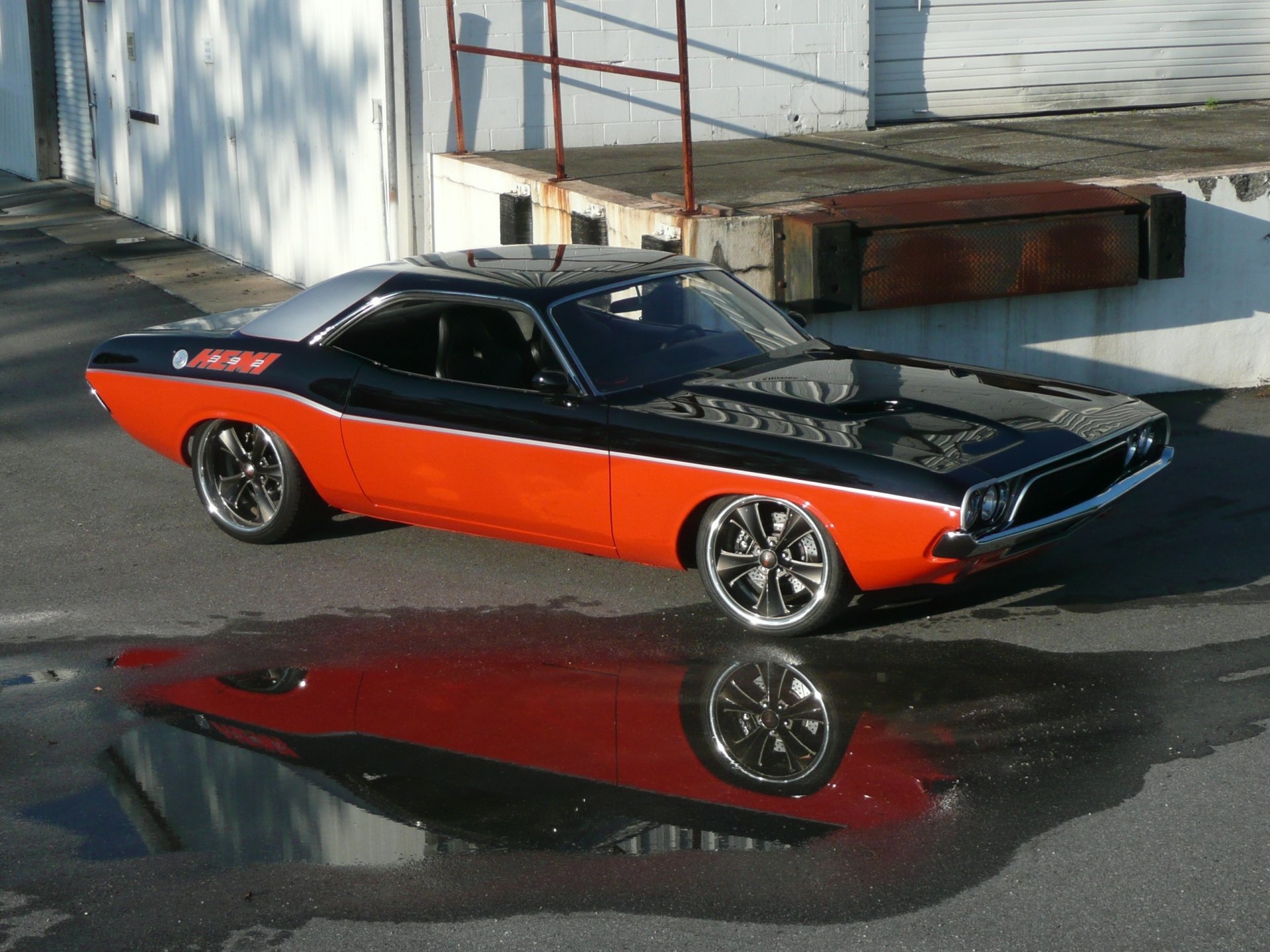 Two-tone orange and black Dodge Challenger, front-quarter view with puddle reflection — 2K Quad HD PC Desktop Wallpaper and Background.