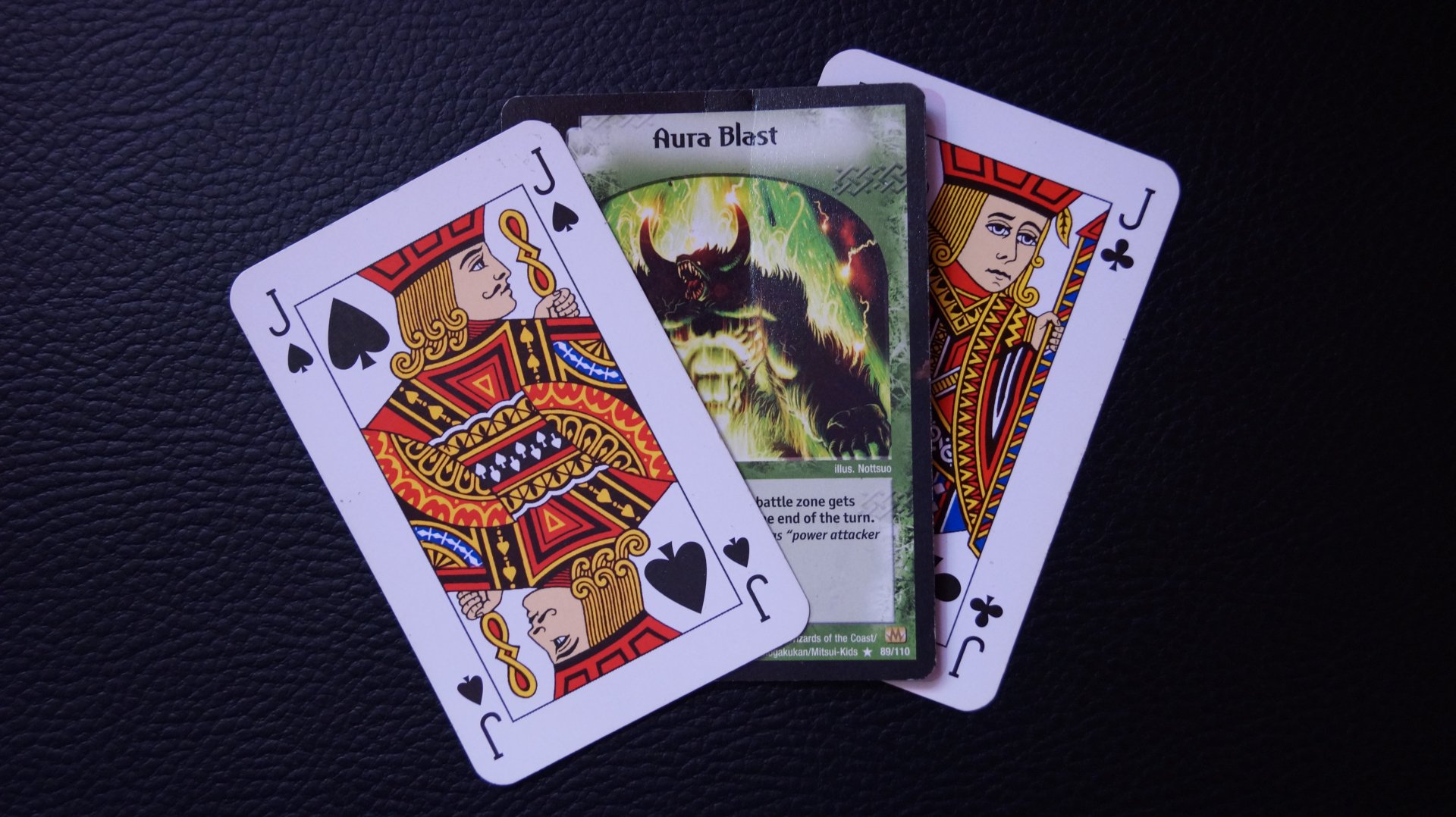 A 4K Ultra HD wallpaper featuring the Aura Blast card from DuelMasters, surrounded by playing cards on a sleek leather background.