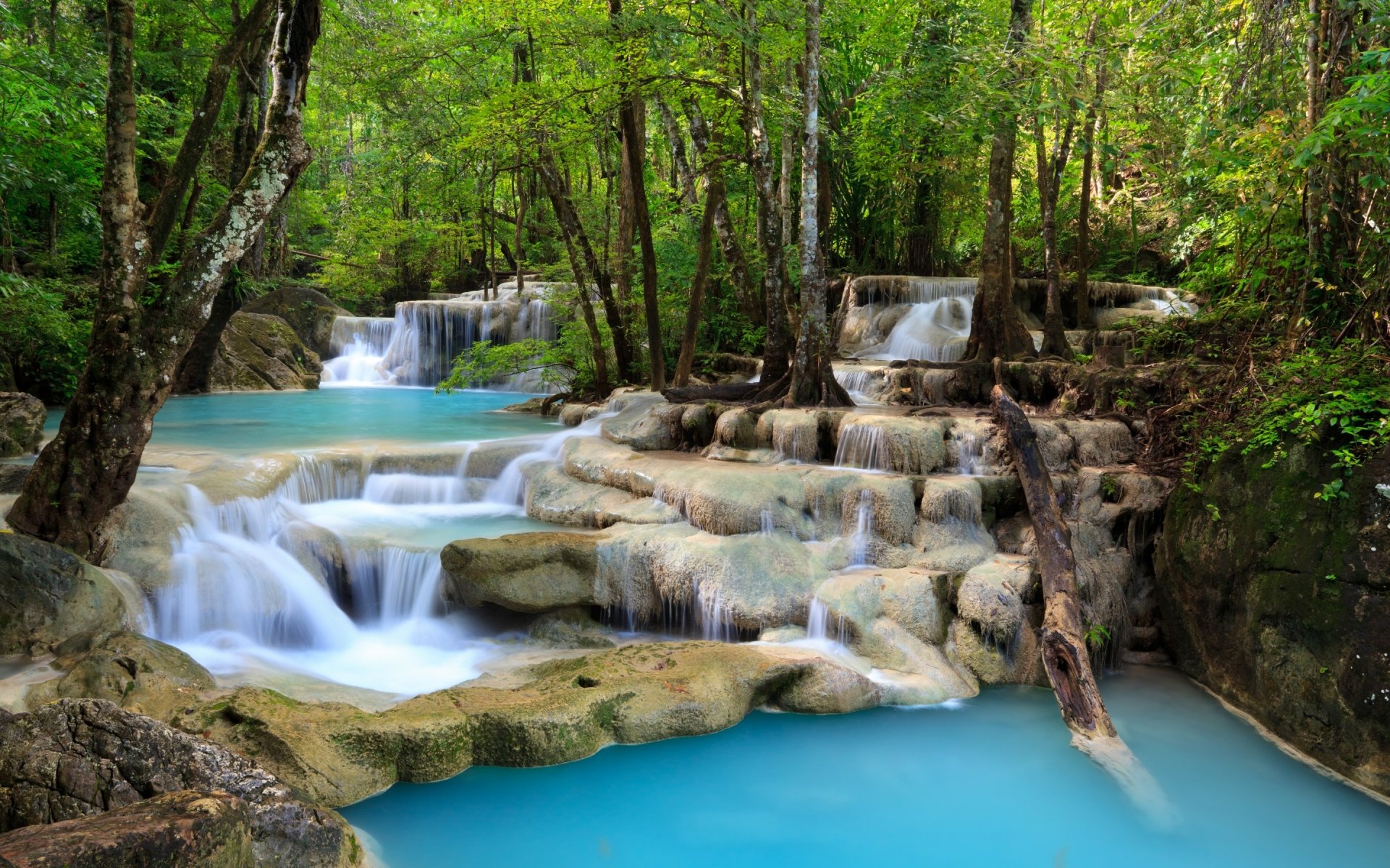 HD PC desktop wallpaper featuring a serene waterfall cascading through lush green forest with turquoise water flowing over smooth rocks.