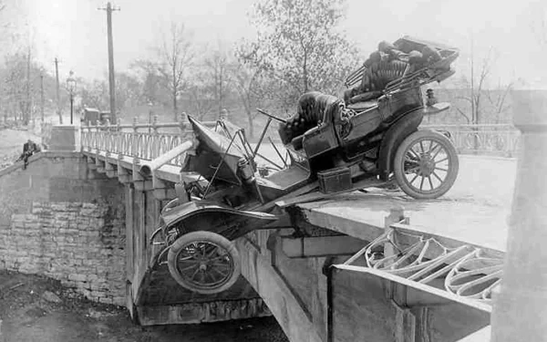 Black and white HD desktop wallpaper featuring a vintage Ford Model T precariously hanging off a broken bridge, showcasing early 20th-century vehicle history.