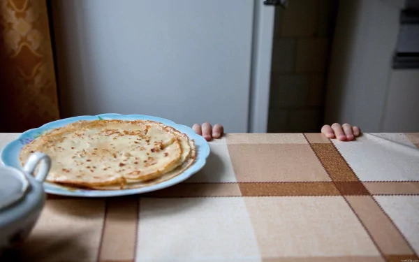2K Quad HD PC desktop wallpaper/background of food: a crêpe on a plate on a checkered tablecloth, small hands peeking over the table edge.