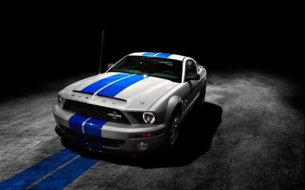 A sleek Ford Mustang Shelby GT500 stands prominently against a dark backdrop, showcasing its distinctive blue racing stripes. This image serves as a dynamic HD desktop wallpaper.