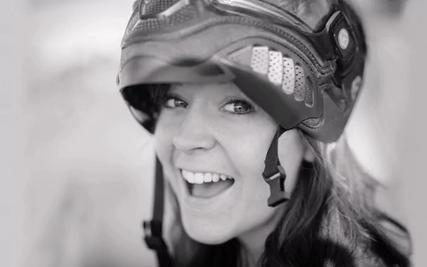 A cheerful woman wearing a helmet smiles brightly, embodying the spirit of music and adventure, set against a stylish HD PC desktop wallpaper background.