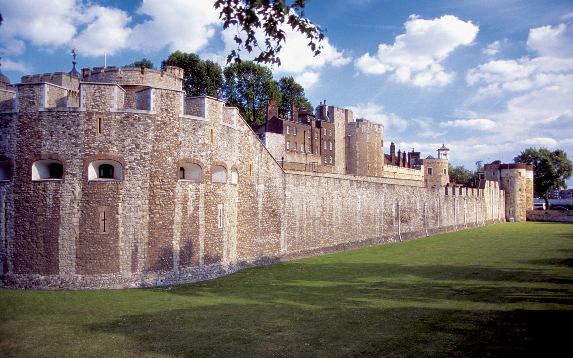 HD PC desktop wallpaper featuring a majestic man-made castle with stone walls under a blue sky dotted with clouds.