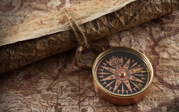 HD PC desktop wallpaper featuring an antique compass resting on a detailed, aged map with a rolled parchment in the background, evoking exploration and adventure.