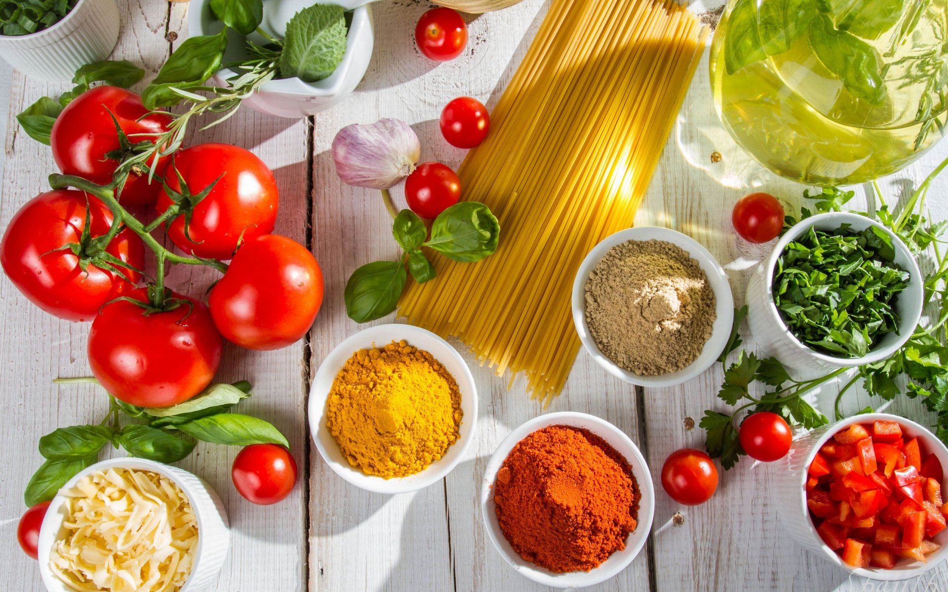 HD PC desktop wallpaper featuring a still life of fresh tomatoes, garlic, herbs, spices, and uncooked spaghetti arranged on a white wooden surface.