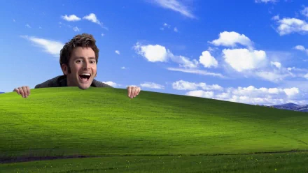 A whimsical HD wallpaper featuring a joyful character from Doctor Who (2005) peeking over a vibrant green hill under a bright blue sky with fluffy clouds.