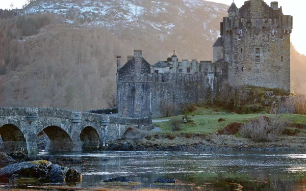 Eilean Donan Castle stands majestically by the water, surrounded by scenic mountains, captured in stunning detail, making an impressive HD desktop wallpaper.