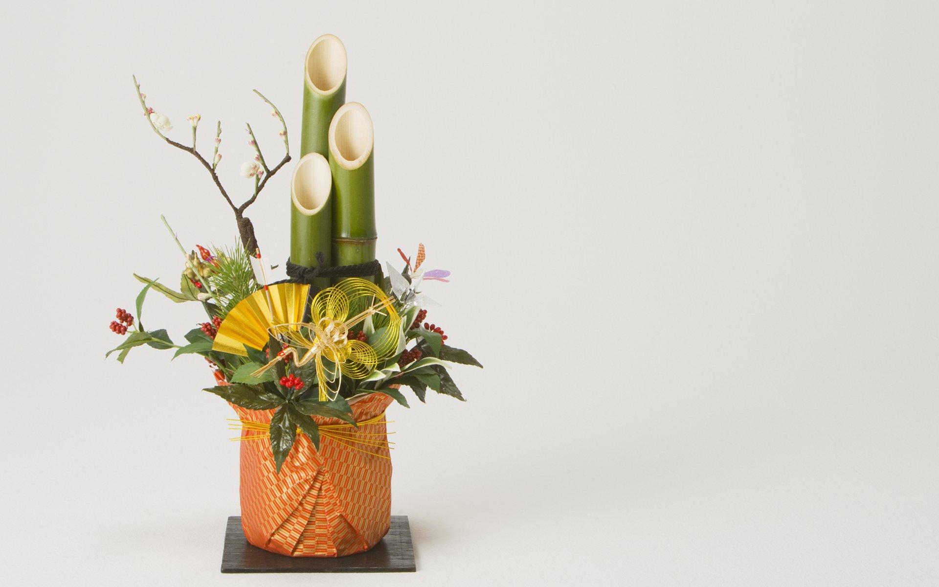 A vibrant still life bouquet featuring bamboo, delicate flowers, and foliage, set in an orange container, captured in high definition for an elegant desktop wallpaper.